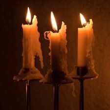 three lit candles sitting in front of a wall