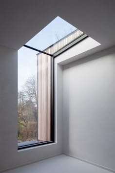 an empty room with a large window and skylight on the wall, overlooking a wooded area