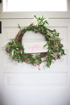 a white door with a wreath hanging on it and the word gather written in pink