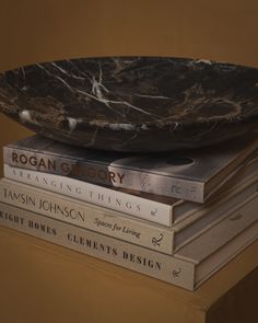 a stack of books sitting on top of each other next to a black marble bowl