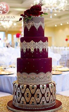 a three tiered purple wedding cake on top of a gold table cloth covered table