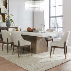 a dining room table with white chairs and a chandelier hanging from the ceiling