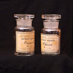 two small bottles with labels on them sitting next to each other in front of a black background