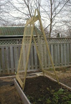 an outdoor garden area with a wooden swing set and various plants in the ground, next to a fence