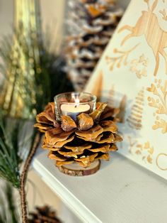 a pine cone candle is sitting on a mantle