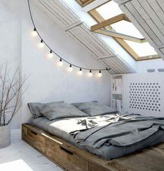 a bed sitting under a skylight in a room with white walls and wooden flooring