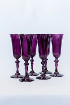 four purple wine glasses sitting next to each other