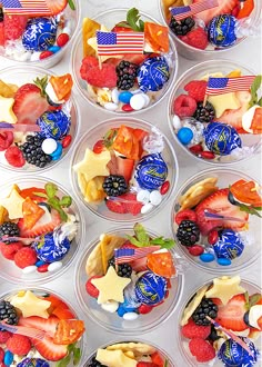 six plastic cups filled with different types of fruit and candy on top of each other