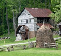 an old barn with a water wheel next to it