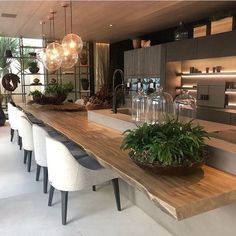 a long table with chairs and plants on it in the middle of a living room