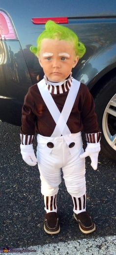 a doll with green hair standing in front of a car wearing white pants and suspenders