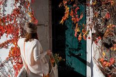 a woman walking down the street carrying a handbag in front of an open door