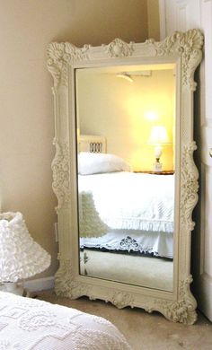 a bedroom with a large white mirror on the floor and a bed in the background