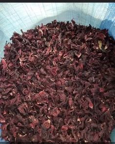 a blue bowl filled with lots of dried red flowers on top of a wooden table