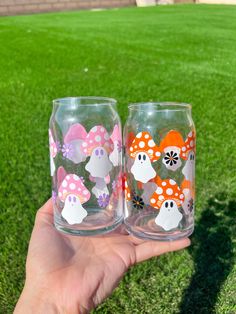 two hand painted glasses sitting on top of a green field