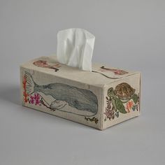 a tissue box with an image of a whale and turtle on it, sitting in front of a gray background