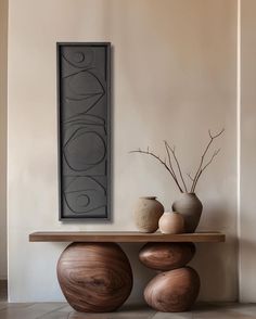 two vases sitting on top of a wooden table in front of a framed painting