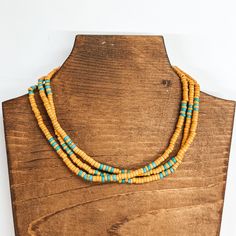 Three strand beaded choker necklace with yellow  and turquoise beads. The necklace is taken on a  brown block and a white background. Yellow Bohemian Beaded Choker Necklace, Yellow Long Bohemian Beaded Necklace, Southwestern Multi-strand Beaded Necklace With Colorful Beads, Handmade Yellow Multi-strand Beaded Necklaces, Yellow Multi-strand Beaded Necklace, Giddy Up Glamour, Beaded Choker Necklace, Beaded Choker, Turquoise Beads