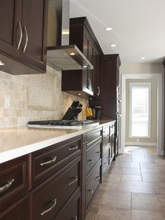 a kitchen with dark wood cabinets and white counter tops, along with tile flooring