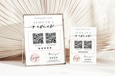 two business cards with qr code on them sitting next to each other in front of a palm tree