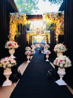 an aisle decorated with white vases filled with flowers and greenery on either side