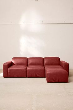 a red couch sitting on top of a white floor next to a wall in a room