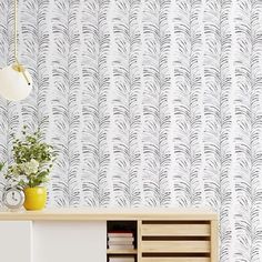 a white cabinet with drawers and a clock on the wall next to it in front of a patterned wallpaper