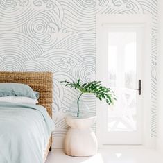 a bed sitting next to a white door in a room with blue wall paper on the walls