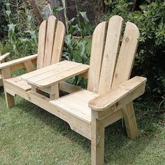 two wooden lawn chairs sitting in the grass