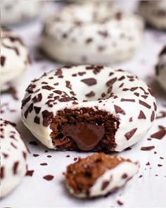 chocolate covered donuts with white frosting and sprinkles on a table