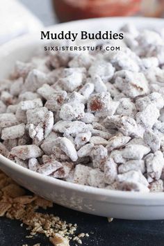 muddy buddies in a white bowl on top of a black counter with the words muddy buddies next to it