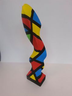 a colorful sculpture sitting on top of a white table next to a black and yellow vase