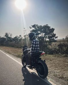 a man riding on the back of a motorcycle down a road