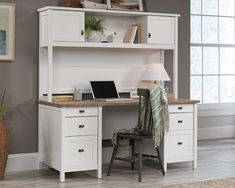 a white desk with a laptop on top of it next to a chair and lamp