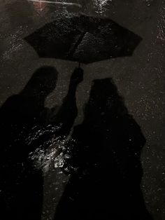 two people standing under an umbrella in the rain on a rainy day with their shadows