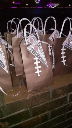 brown paper bags with footballs on them are lined up against a brick wall at night