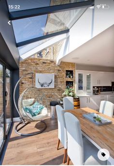 a dining room table with chairs and a hanging egg chair in front of an open floor plan