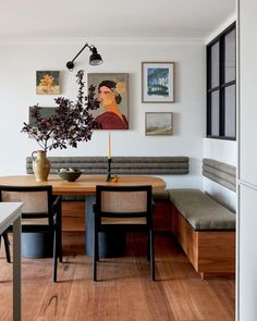 a dining room table and bench with pictures on the wall