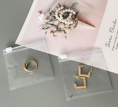 two pieces of jewelry sitting on top of a table next to a card and envelope