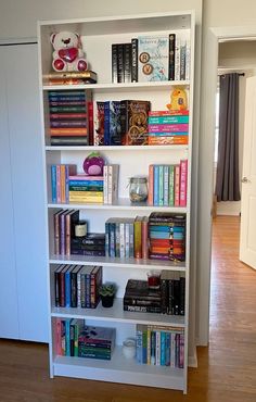 a book shelf filled with lots of books on top of a hard wood floor