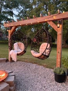 two hanging chairs in front of a fire pit