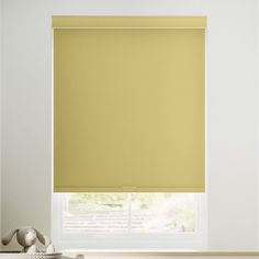 a yellow roller shade in a white room with a teddy bear on the window sill