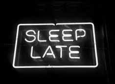 a neon sign that says sleep late in white letters on a black background with the word's underneath it