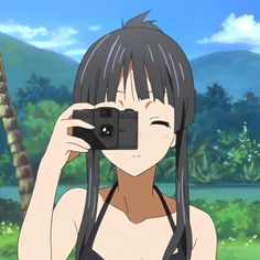 a girl with long black hair holding a camera up to her face and looking into the distance