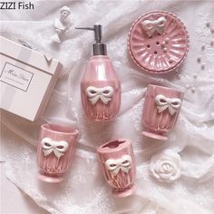 pink bathroom accessories with white bows on them and soap dispenser in the middle