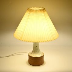 a table lamp with a wooden base and a white shade on the top that is turned off