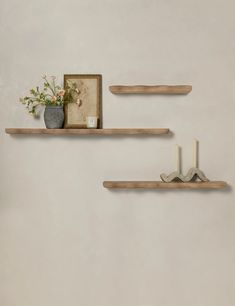 two wooden shelves on the wall with flowers and candles in vases next to them