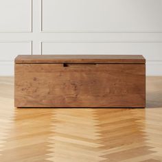 a wooden box sitting on top of a hard wood floor next to a white wall