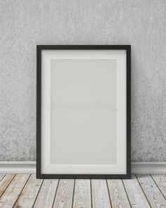 an empty black frame on the floor in front of a wall with wood planks