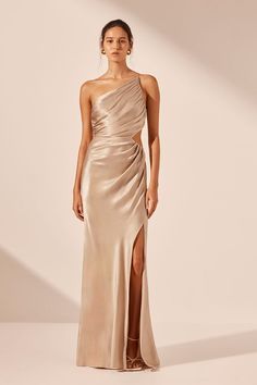 a woman in a gold one shoulder dress with slits on the side and an open back